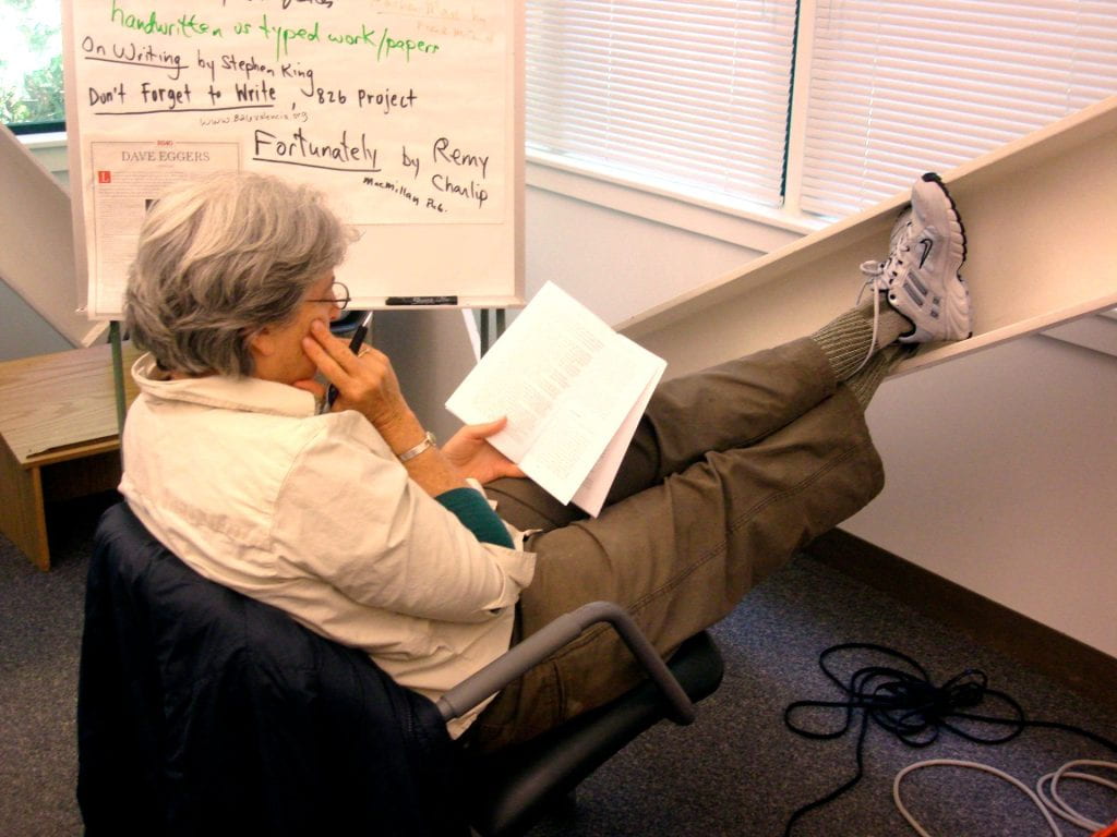 A person sitting on a chair reading a book.