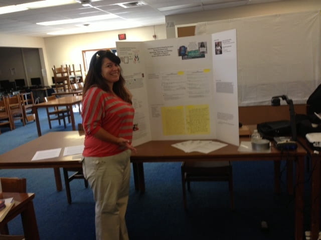 A women standing next to a poster up on a table.